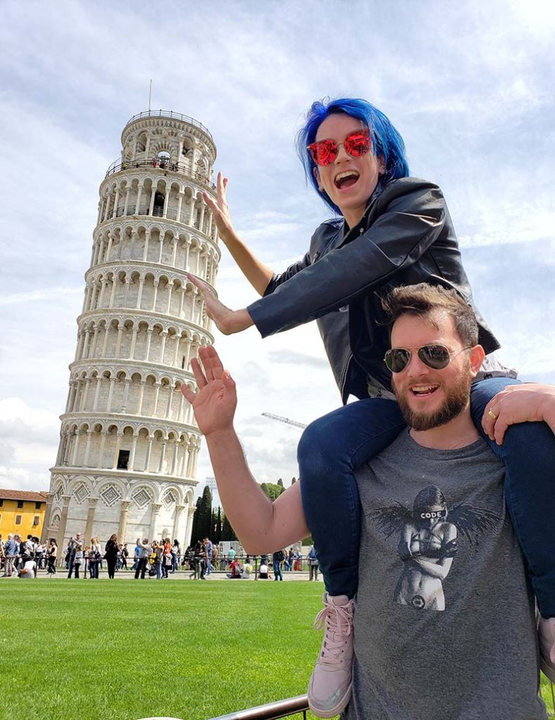 mulher nos ombros de homem segurando a torre de pisa na italia