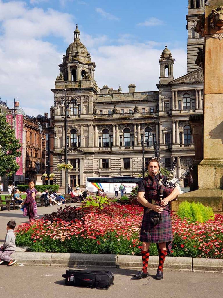 Escocês tocando gaita de fole vestido com kilt na George Square em Glasgow