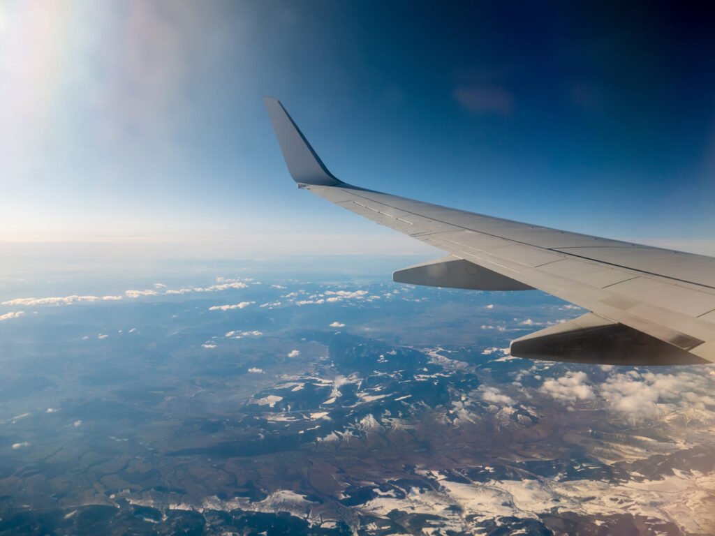 Vista da asa do avião sobre montanhas, reforçando que ao planejar viagem sozinho ou com consultoria o essencial é viver uma experiência com a sua cara