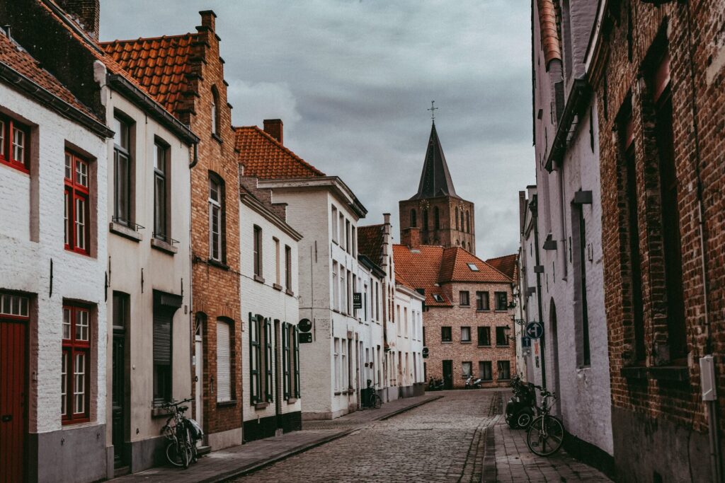 Rua tranquila em uma cidade histórica da Bélgica com casas de tijolos e bicicletas, simbolizando os benefícios do slow travel na Europa