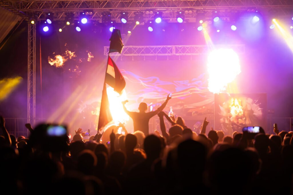 Multidão com bandeira diante de palco com pirotecnia no Eurosonic Noorderslag, em Groningen (Holanda); guia dos principais Festivais de música na Europa.