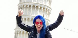 O que fazer em Pisa na Itália: roteiro de viagem mulher de cabelo azul fazendo pose de luta em frente a torre inclinada